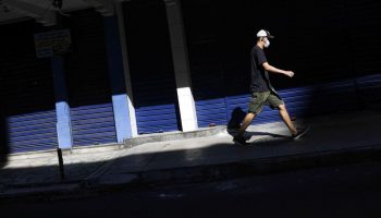 Um homem usando uma máscara protetora passa por um comércio fechado na cidade de Niterói