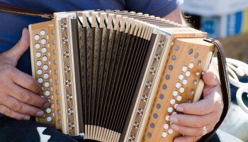 A closeup shot of a male playing the accordion